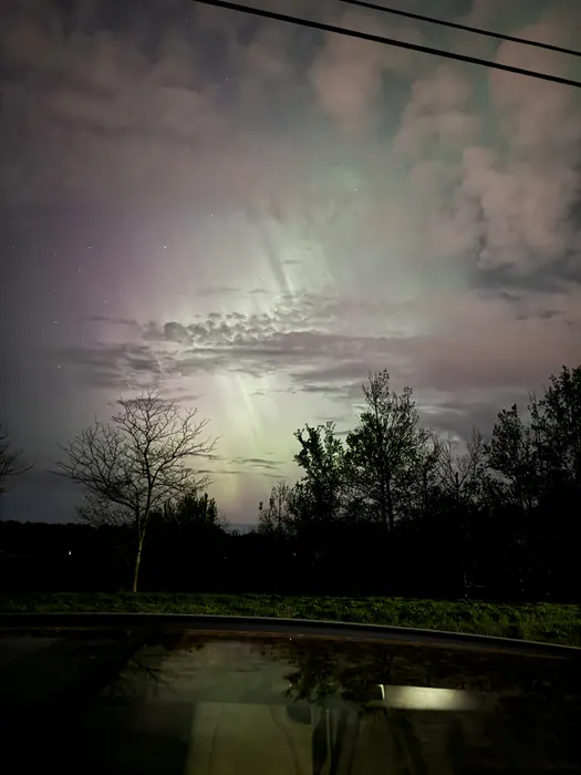The Northern Lights! This depicts the Northern Lights above a car and trees.