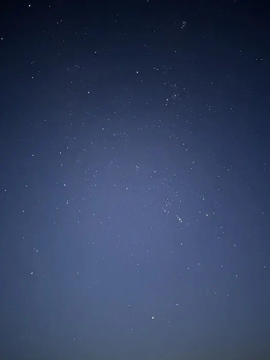 This is a wide angle shot of the sky, it contains the Pleiades Cluster in the top right! This image depicts many stars in a bright sky.