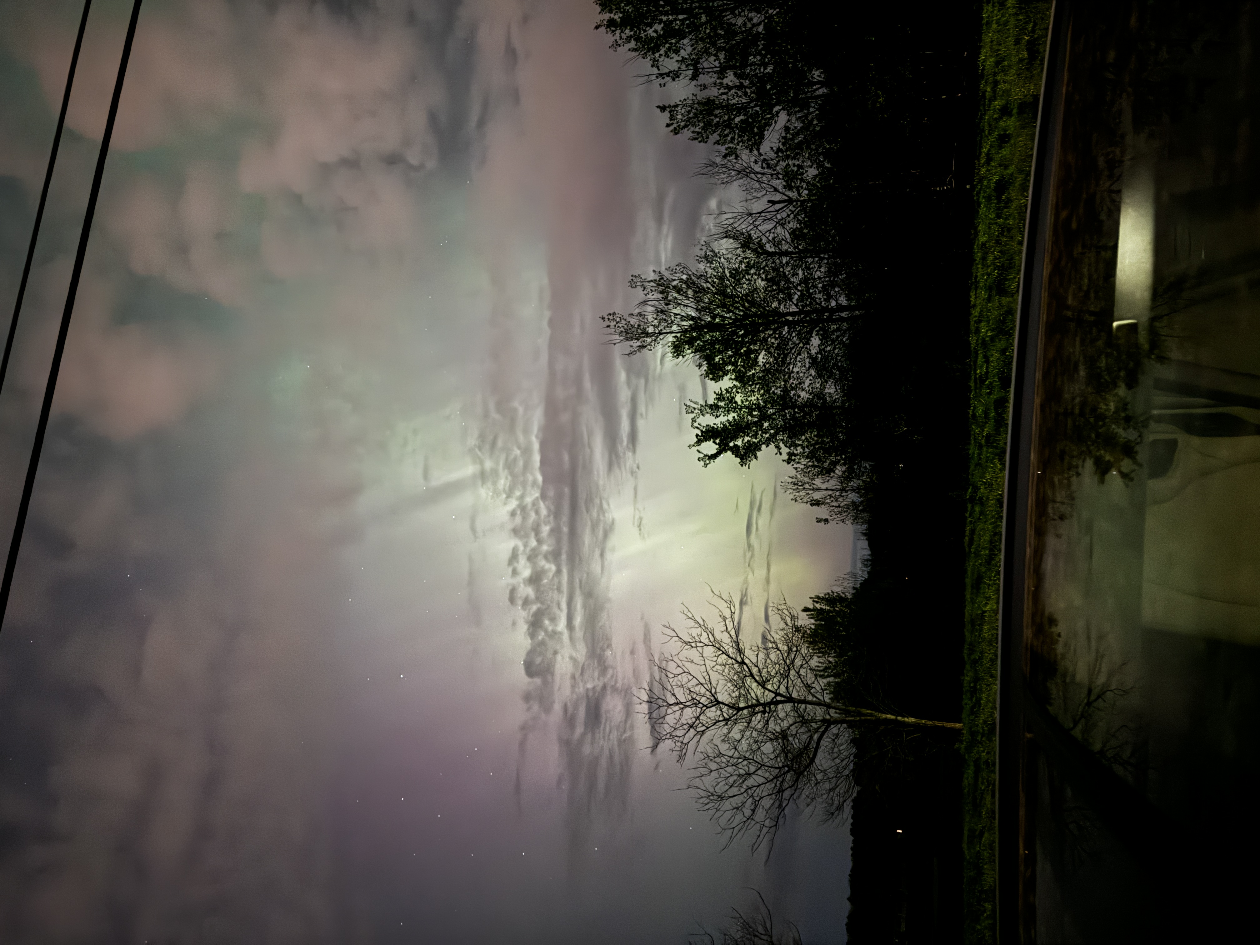 The Northern Lights! This depicts the Northern Lights above a car and trees.