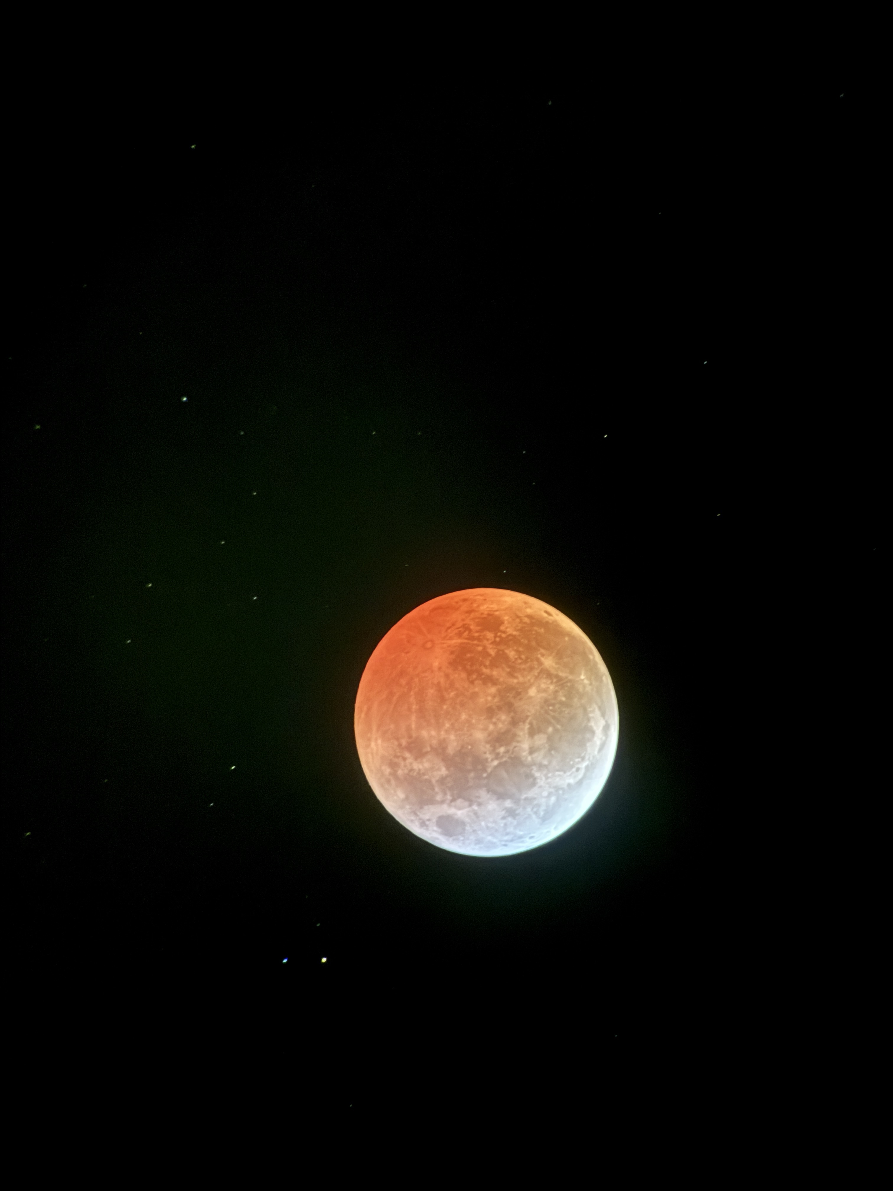 One of many images from the lunar eclipse in March of 2025. This depicts the moon with the upper three quarters tinted orange by a lunar eclipse and the bottom crescent white.