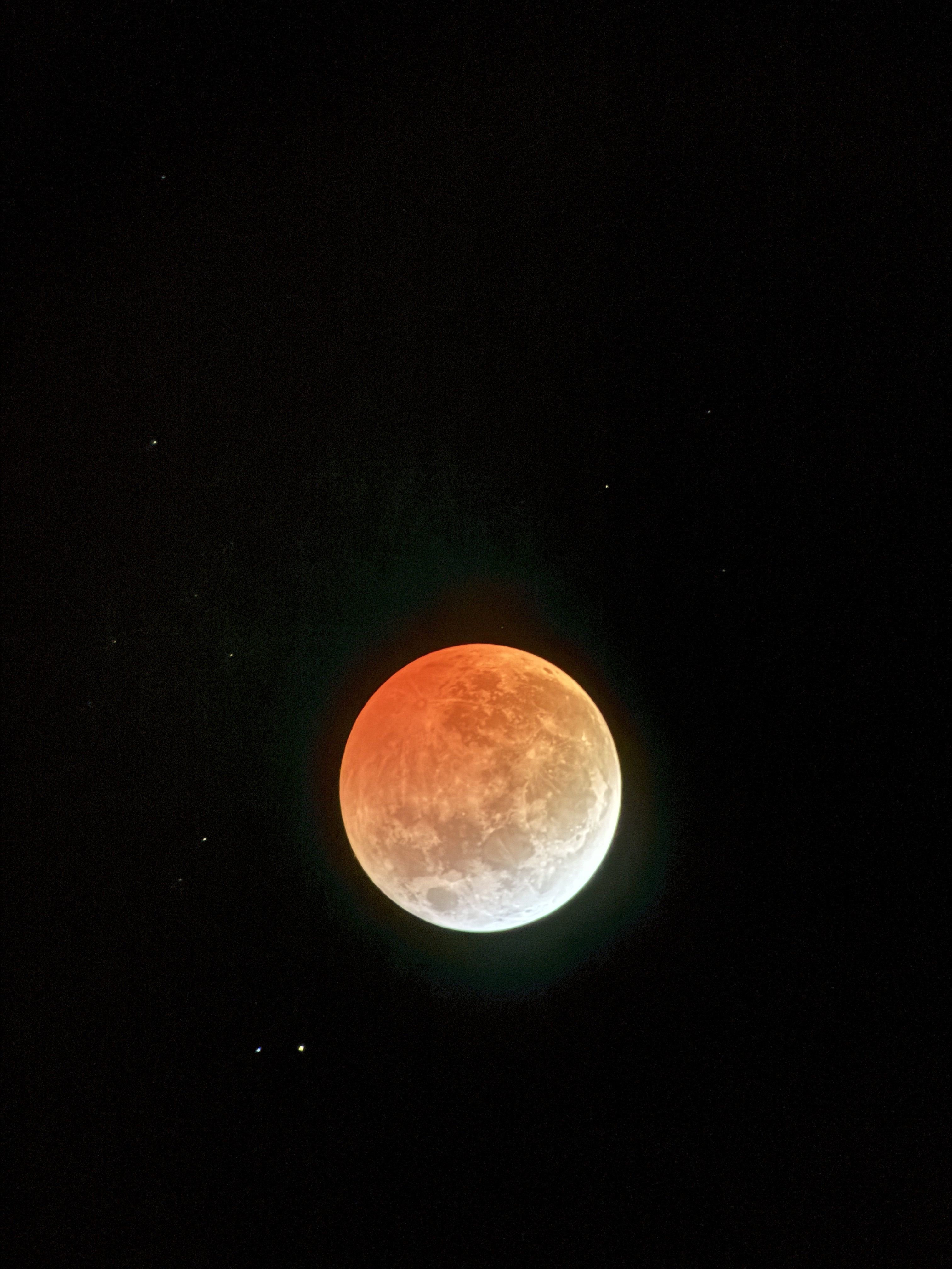 One of many images from the lunar eclipse in March of 2025. This depicts the moon with the upper three quarters tinted orange by a lunar eclipse and the bottom crescent white.