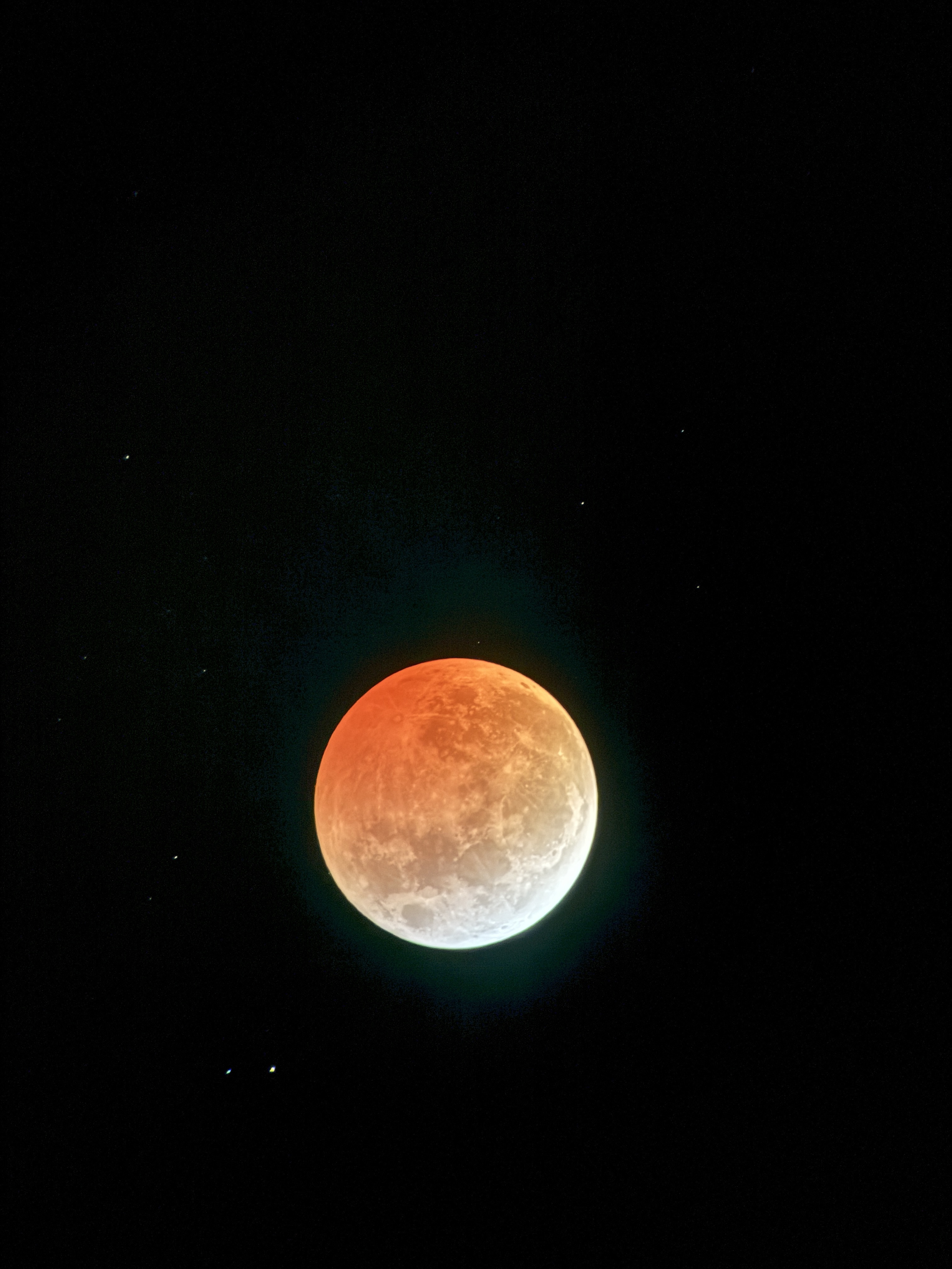One of many images from the lunar eclipse in March of 2025. This depicts the moon with the upper three quarters tinted orange by a lunar eclipse and the bottom crescent white.
