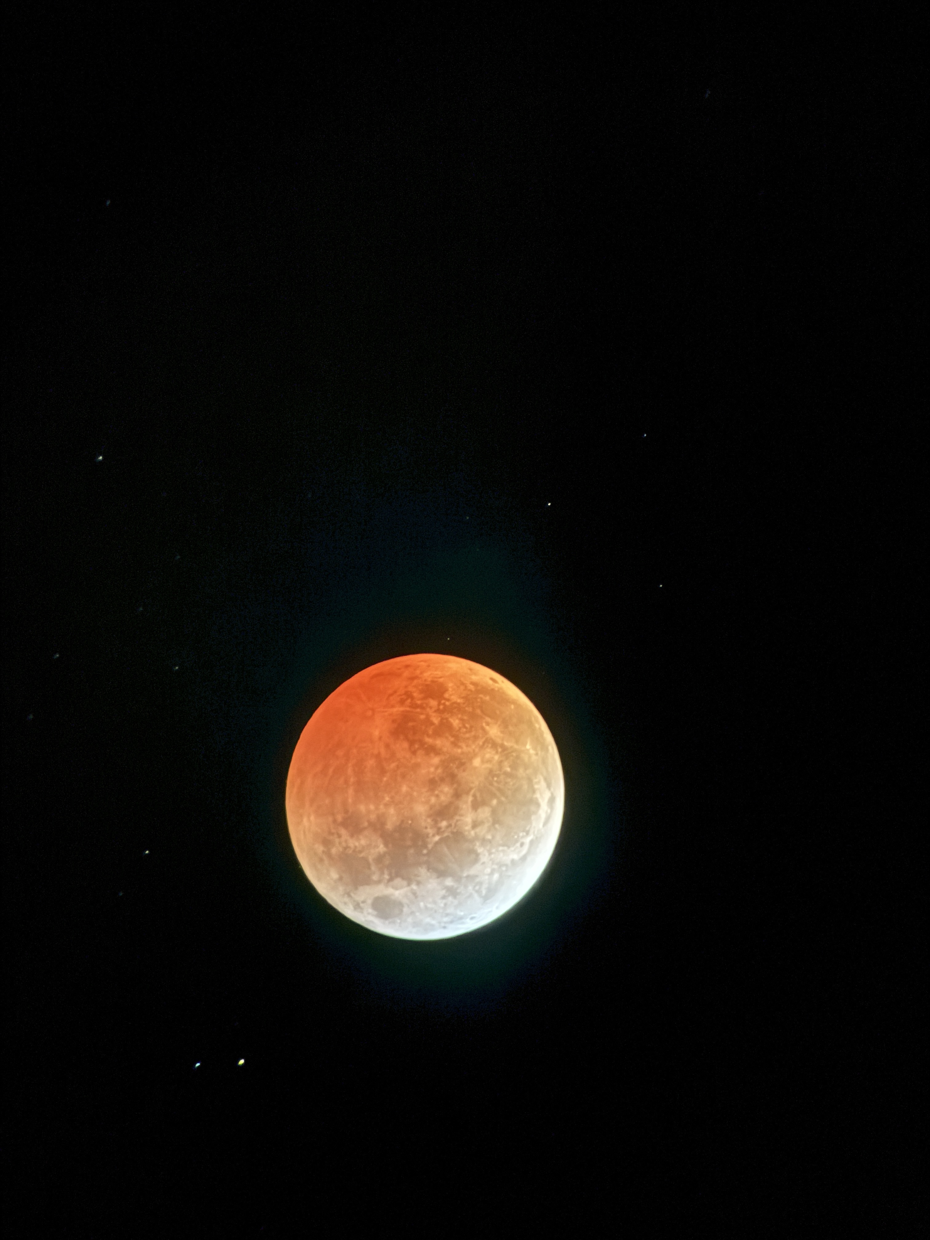 One of many images from the lunar eclipse in March of 2025. This depicts the moon with the upper three quarters tinted orange by a lunar eclipse and the bottom crescent white.