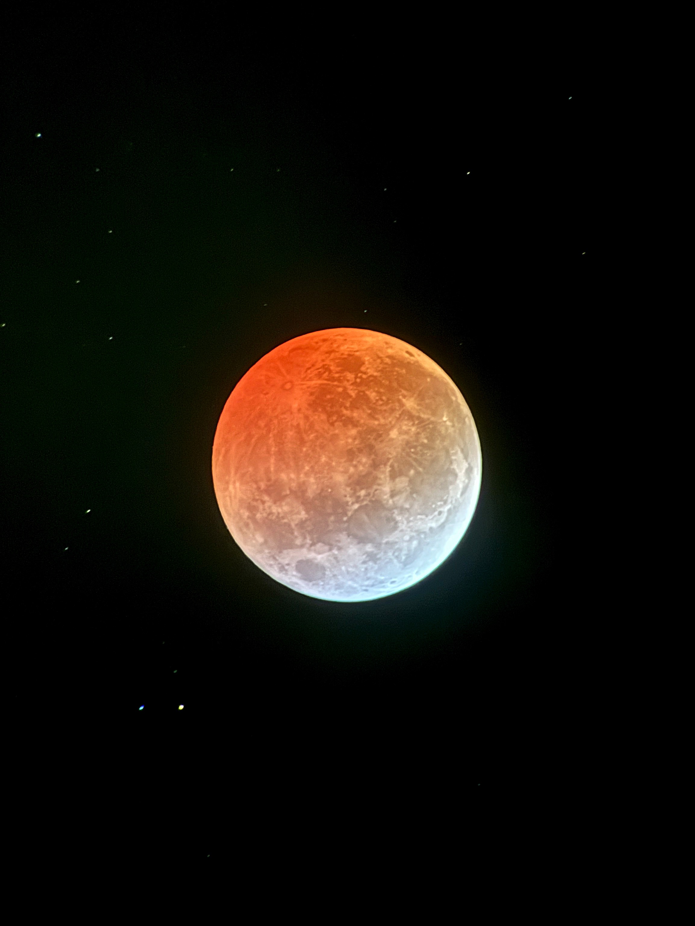 One of many images from the lunar eclipse in March of 2025. This depicts the moon with the upper three quarters tinted orange by a lunar eclipse and the bottom crescent white.